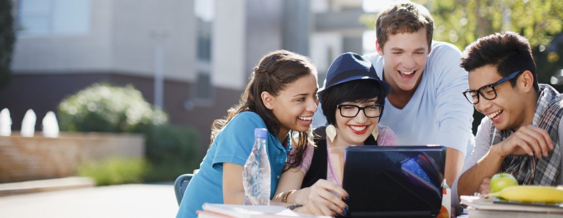 Students using laptop together outdoors